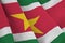 Suriname flag with big folds waving close up under the studio light indoors. The official symbols and colors in banner