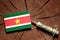 Suriname flag on a stump with syringe injecting money