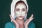 Surpised beauty woman. Skin care, spa, wellness. Girl face with cucumber mask on green background.