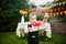 Surprise for the birthday. the boy is holding a box with a gift in the yard on the background of a festive table with a cake. dres