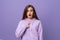 Surprise and puzzled young brunette woman pointing finger at herself, stands over purple background with open mouth. Young