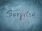 Surprise, word written on blue sand