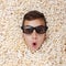 Surprise young boy in stereo glasses looking out of popcorn