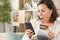 Surprised adult woman paying on phone with card at home