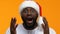 Surprised afro-american man in christmas hat on yellow background, announcement