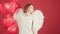 Surprised angel woman holding balloon at studio. Funny angel girl with red hearts on red background isolated. Young