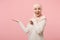 Surprised arabian muslim woman in hijab light clothes posing isolated on pink background in studio. People religious