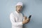 Surprised Balinese man wearing udeng or traditional headband and white shirt holding his smartphone, isolated by blue background