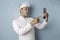 Surprised Balinese man wearing udeng or traditional headband and white shirt holding his smartphone, isolated by blue background