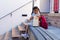 Surprised biracial schoolgirl sitting on bench and opening lunch outside elementary school