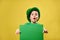 Surprised boy in green Irish leprechaun hat poses wit a green sheet of paper in his hands. Saint Patrick`s Day concept. Yellow