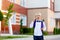 Surprised boy schoolboy blond in glasses with a backpack stands at the school and shows a thumbs up. Day of knowledge