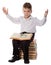 Surprised boy sitting on pile of books with magnifyer