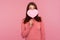 Surprised brunette woman in pink sweater covering face with pink heart, hiding behind symbol of love, wondered with romance date