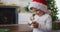 Surprised caucasian boy wearing santa hat playing with snow globe