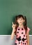surprised child girl show with a finger empty school blackboard, copy space