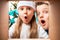 Surprised children in a Christmas hat with funny faces look into a box with a Christmas or new year`s gift, on the background of