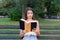 Surprised confused and with widely open eyes woman is reading a book on the bench in the park