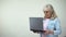 Surprised elderly female reading message on laptop, good news, communication