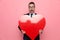 Surprised elegant man in suit holding big red heart