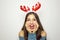 Surprised excited christmas woman on gray background. Beautiful happy christmas girl with reindeer horns on her head.