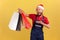 Surprised excited courier in blue uniform and santa claus hat demonstrating paper bags, express delivery from store