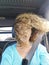 Surprised face expression adult beautiful woman inside the car with safety belot  and wind moving the curly hair - people and