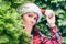 Surprised face woman in a santa claus red hat looks away through green fir tree branches in the forest. Christmas coming, sale