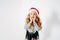 Surprised fashionably dressed curly hair tween girl in santa hat, denim jacket and black tutu skirt on white background with