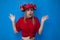 Surprised funny girl fan in red clothes and with a beer hat on a blue background shrugs, fan shrugs