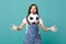 Surprised funny young woman football fan cheer up support favorite team throwing soccer ball isolated on blue turquoise