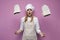 Surprised girl cook in apron throws out gloves for baking on a pink background