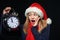 Surprised girl in Santa hat with alarm clock