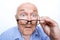 Surprised grandfather holding glasses