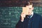 Surprised guy hiding his face behind book cover. Portrait of young scholar isolated on blurred green background