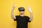 Surprised guy with VR glasses touches virtual space on a yellow background, using modern virtual reality gadgets