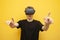 Surprised guy with VR glasses touches virtual space on a yellow background, using modern virtual reality gadgets