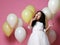 Surprised kid girl with balloons in princess dress with tiara holds balloon