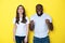 Surprised lucky interracial couple in white T-shirts posing for camera in studio