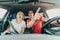 Surprised man and impressed woman point fingers at incredible accident while driving car. Shocked people with wide open eyes and