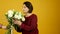 Surprised middle aged woman looking at flowers and taking bouquet with smile