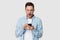 Surprised millennial man holding cellphone looking at telephone screen