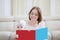 Surprised mother looking her baby girl bites a book