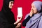 Surprised Muslim women with a smartphone in their hands showing a white mockup screen to the camera. Advertising concept
