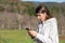 Surprised pretty young woman breathes fresh air in the park listening to music on headphones and holding a smartphone