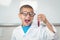 Surprised pupil with lab coat looking at test tube