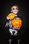 Surprised red haired child in skeleton costume holding a orange pumpkin. Halloween