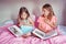 Surprised scared Caucasian sisters girls reading books in bedroom. Home schooling children siblings learned saw unexpected in a