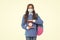 Surprised school child wear protective mask to prevent COVID-19 spread holding alarm clock, deadline