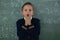 Surprised schoolboy standing against chalkboard